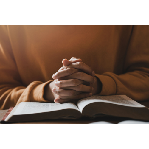 A person's hands is in prayer over a bible expressing faith to God